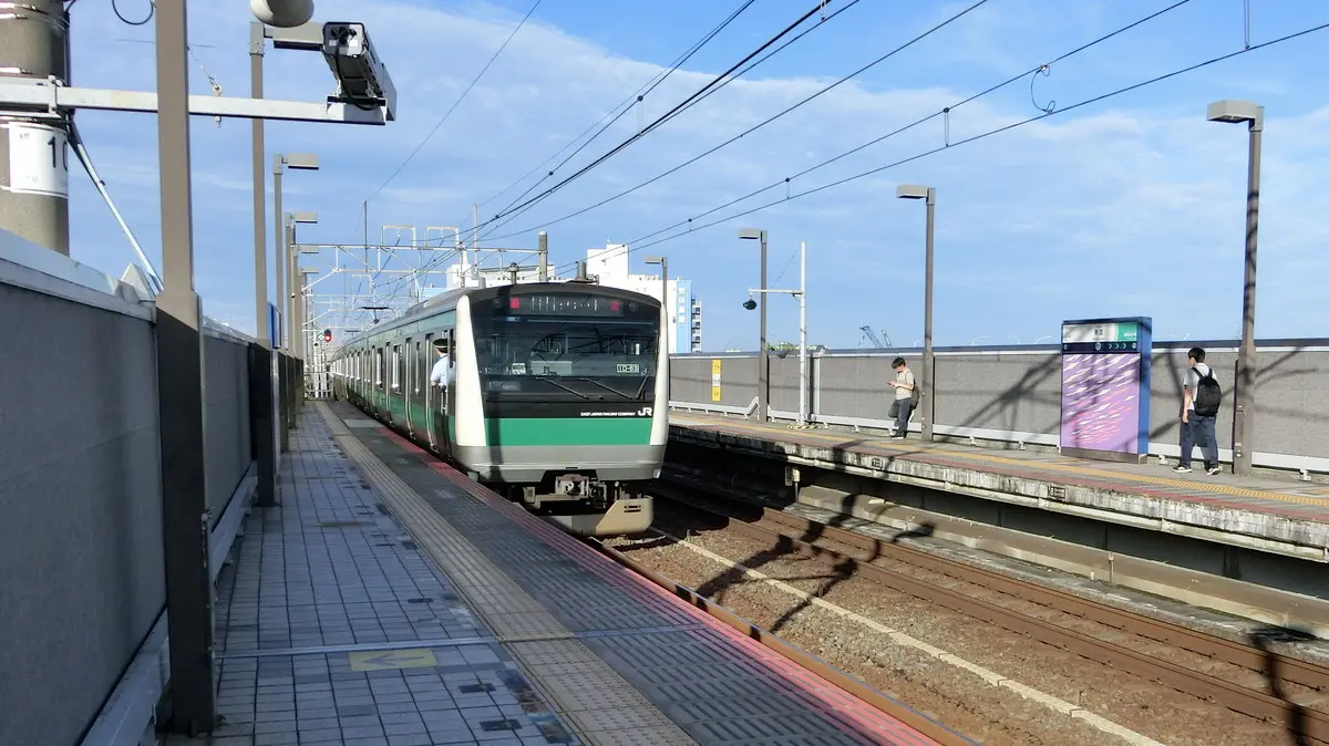 An E233 series train running directly on the Saikyo Line departs from Shinonome Station